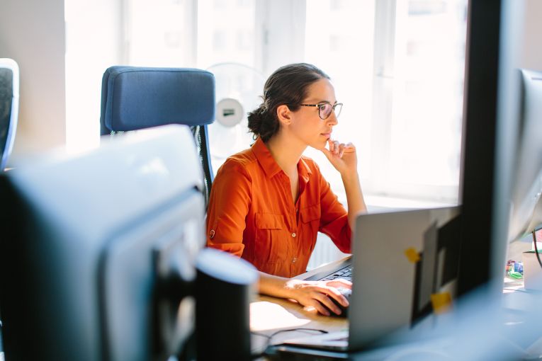 Junge Frau arbeitet mit vollen Fokus am Schreibtisch vor einem PC